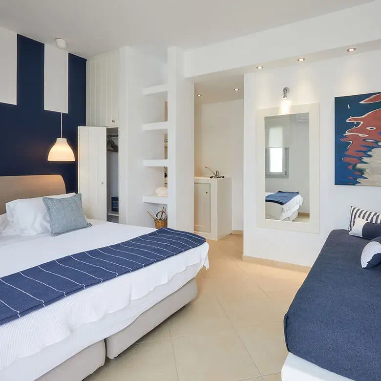 Romantica Suites interior with beds, blue daybed and kitchenette area