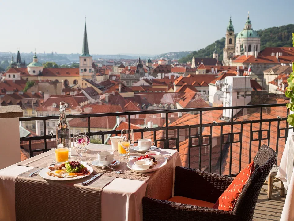 Breakfast table on Golden Well’s shared restaurant terrace overlooking Prague’s red rooftops and church towers.