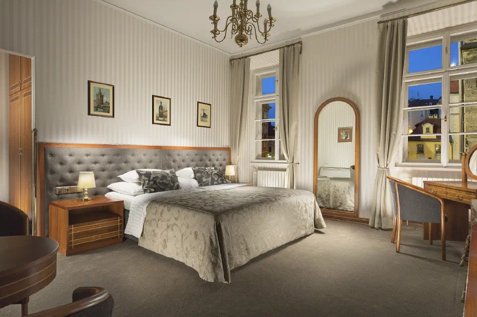 Classic double room at Hotel Pod Věží with a padded headboard and tall windows.