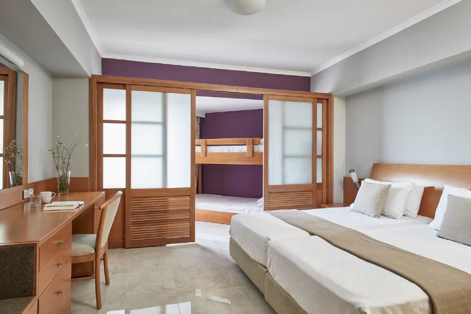 Family Room at Esperides Beach Resort with twin beds and a bunk-bed area behind sliding doors.