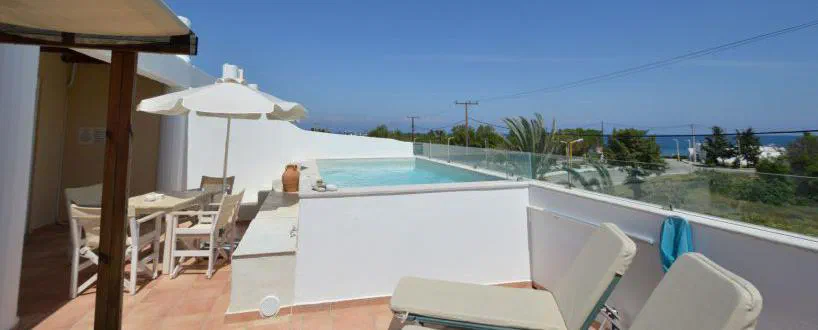 Terrace and small pool of Kathara Bay’s two-bedroom apartment, with the sea beyond the glass balustrade.
