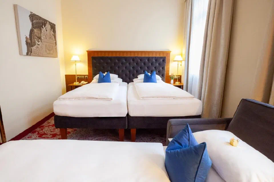 Twin beds in a warmly lit Hotel Kaiserhof Wien guest room.
