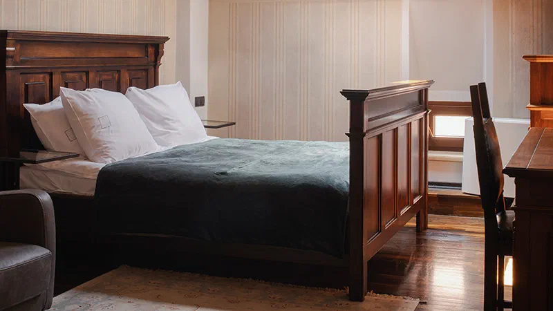 Dark wood bed and muted green cover in a Double Room at Hotel Copernicus.