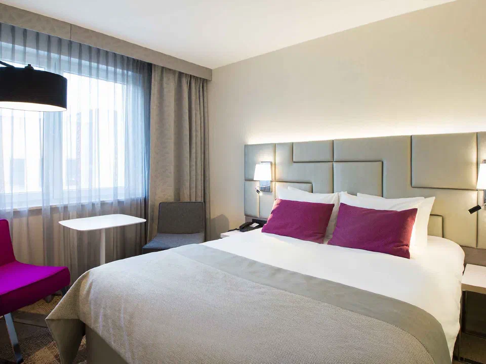 Double bed, purple cushions and window seating in a Classic room at Mercure Krakow Stare Miasto.