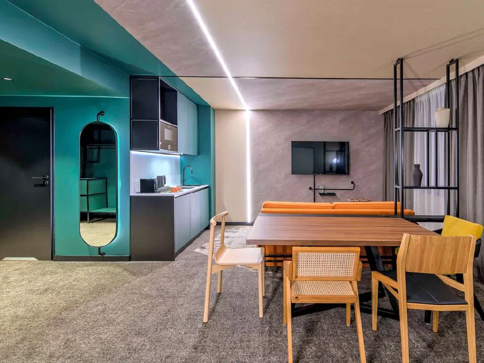 Dining table, orange sofa and kitchenette in a Junior Suite at Novotel Kraków Centrum.