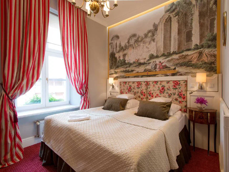 Floral headboard, landscape wall art and red curtains in a Standard Double Room at Hotel Polski Pod Białym Orłem.