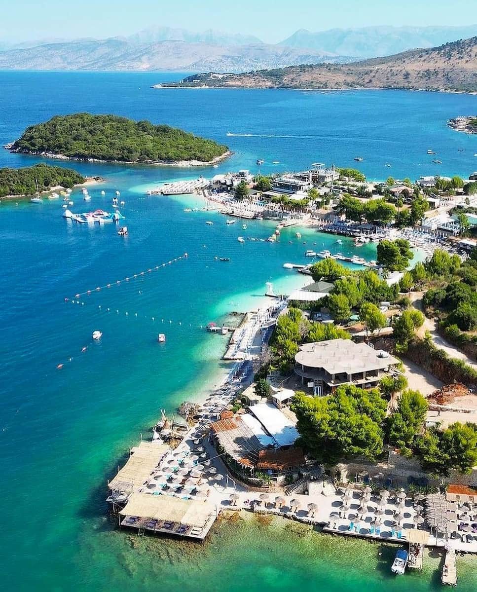 Ksamil centre and its coves from above, with green islets and the Corfu Strait beyond