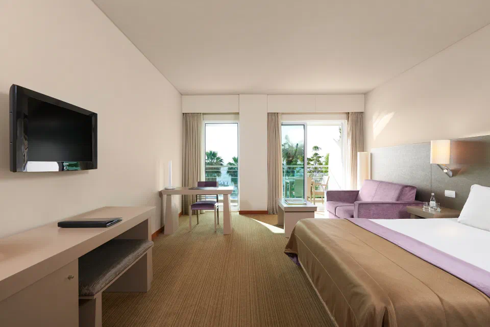 An Ocean View room at Meliá Madeira Mare, with a bed, sofa and doors to a balcony.