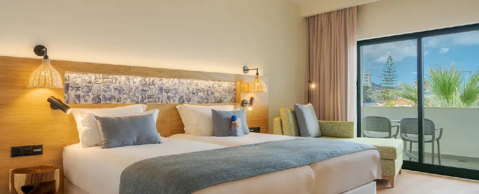 A double room at Sentido Galosol with blue bedding, a tiled headboard and balcony doors.
