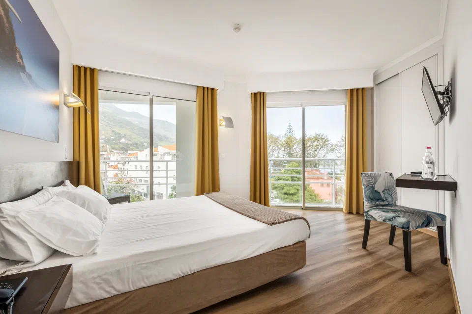 A bright double room at White Waters Hotel, with large windows towards Machico’s hills.