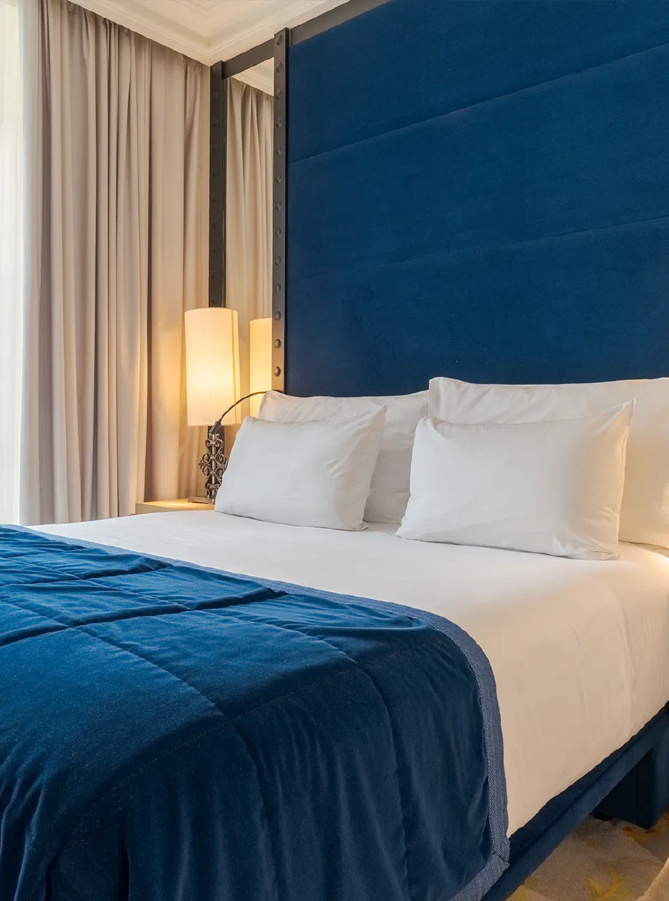 Pestana Collection Plaza Mayor Classic Room bed with blue upholstered headboard and blue bed throw.