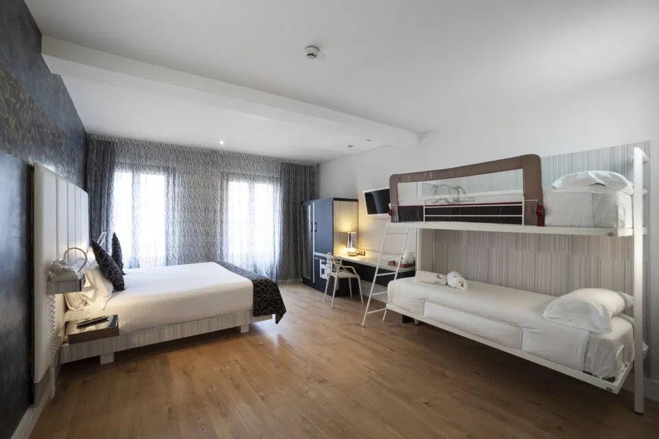 Petit Palace Savoy Alfonso XII quadruple room with a double bed and bunk beds.