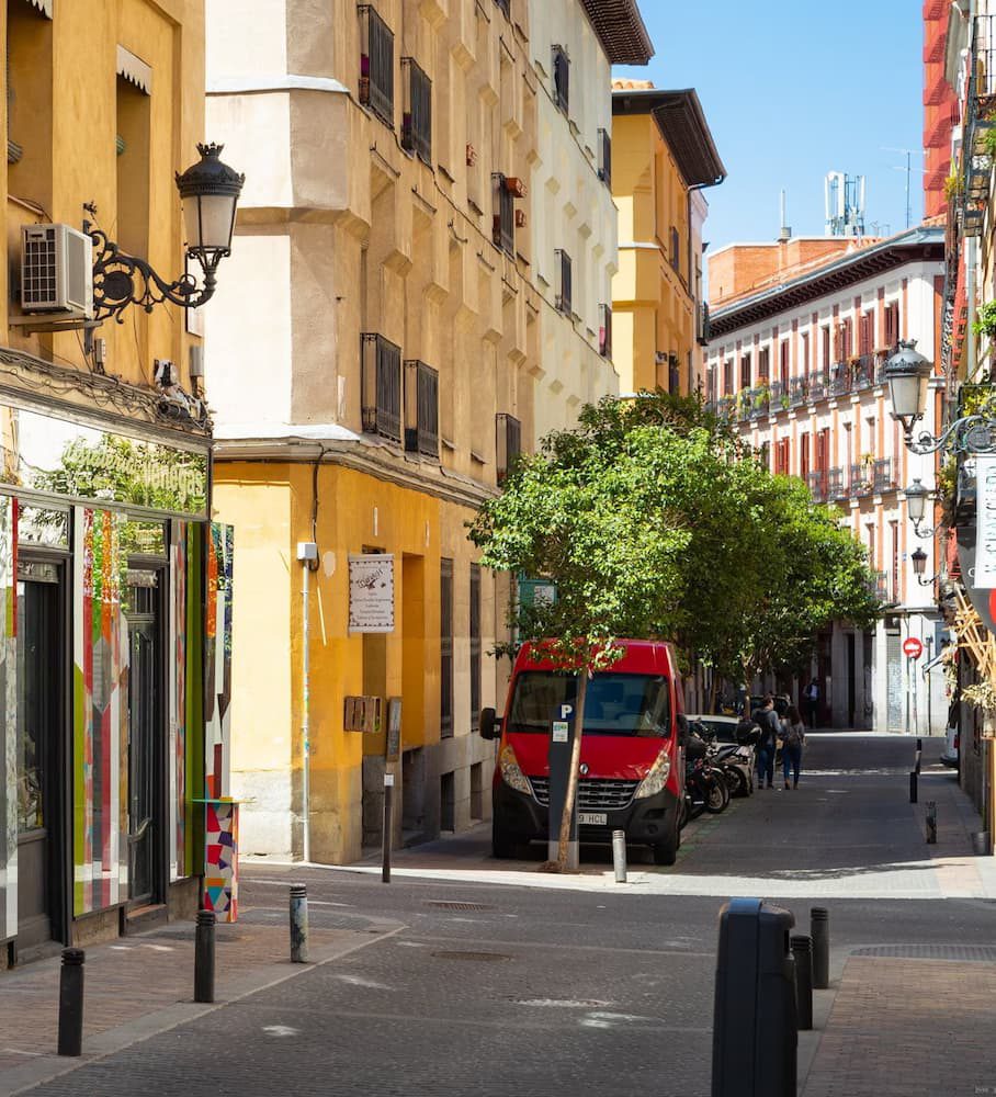 A narrow street in Barrio de las Letras, with yellow façades, iron lamps and balconies.