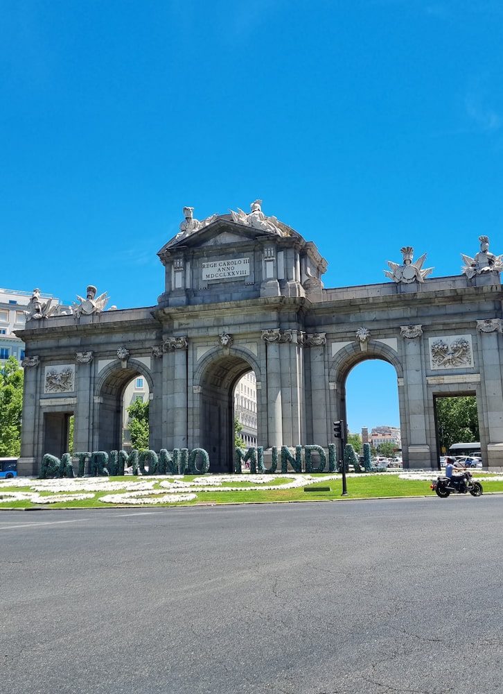 Puerta de Alcalá behind a flowerbed spelling Patrimonio Mundial.