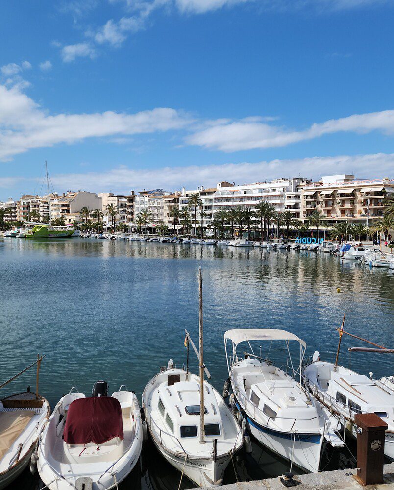 Small boats by Port d’Alcúdia’s harbour and waterfront buildings.