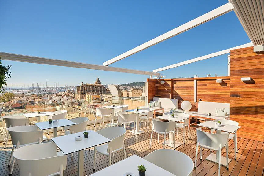 Tables and white chairs on Hotel Almudaina’s rooftop terrace above Palma.