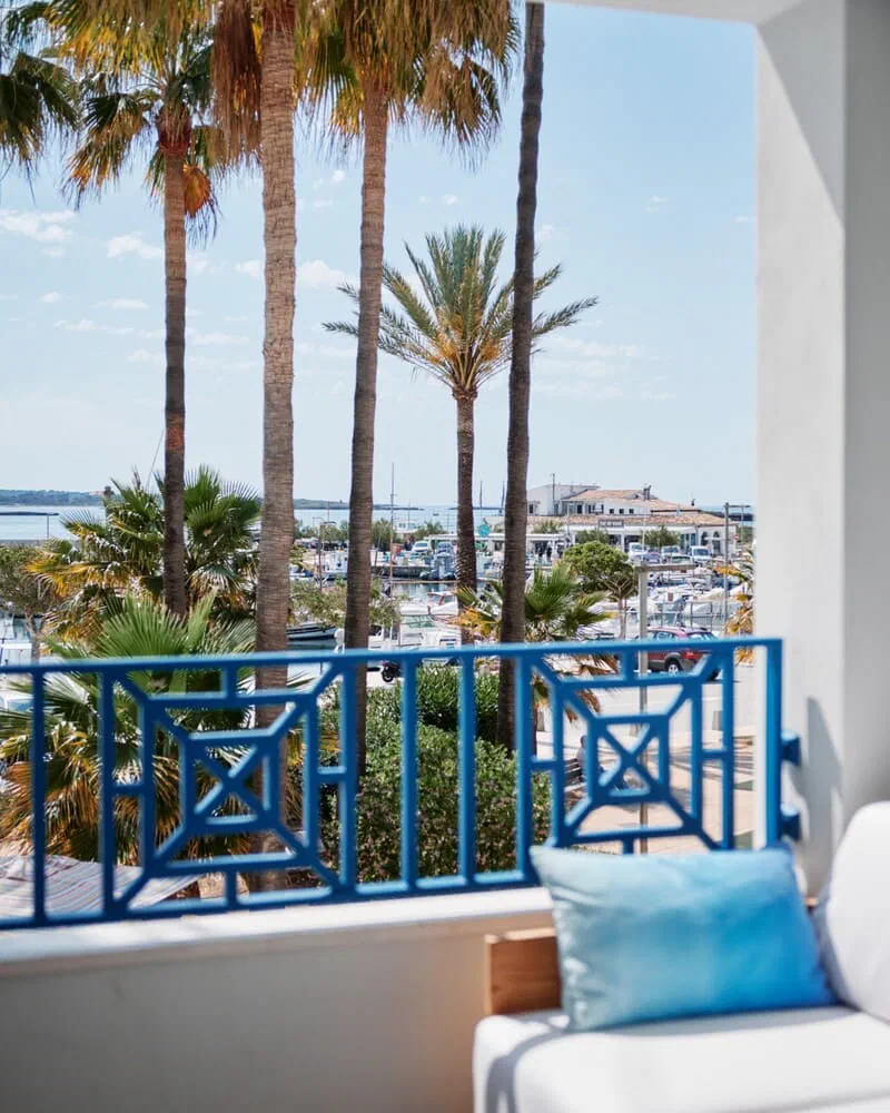 Blue-railed terrace of a Superior Sea View room at Hotel Honucai, facing palms and the harbour.