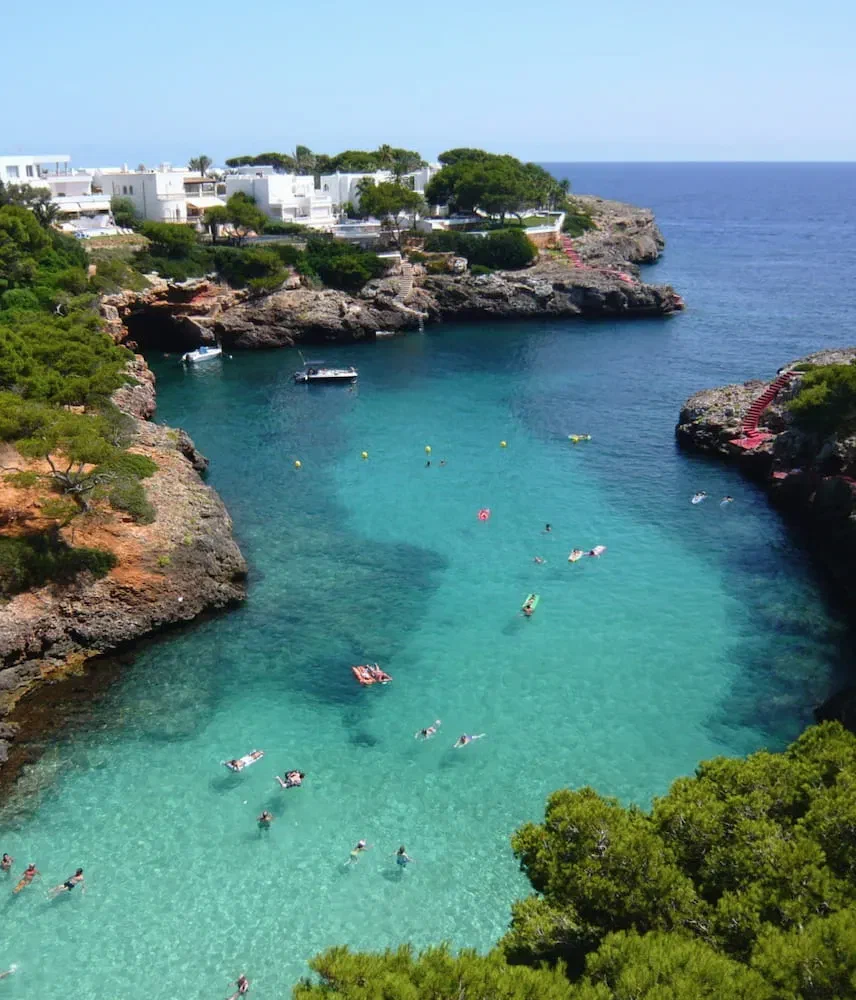 Cala Esmeralda at Cala d’Or, with white villas among pine trees.