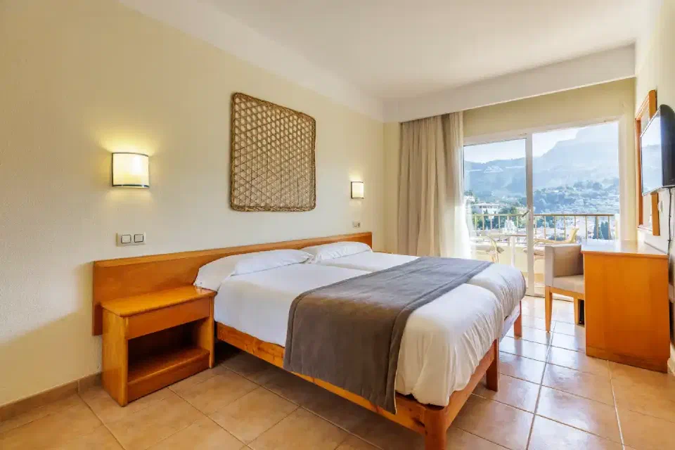 Double bed and balcony doors with mountain views in a Superior Room at Hotel Eden Nord Sóller.