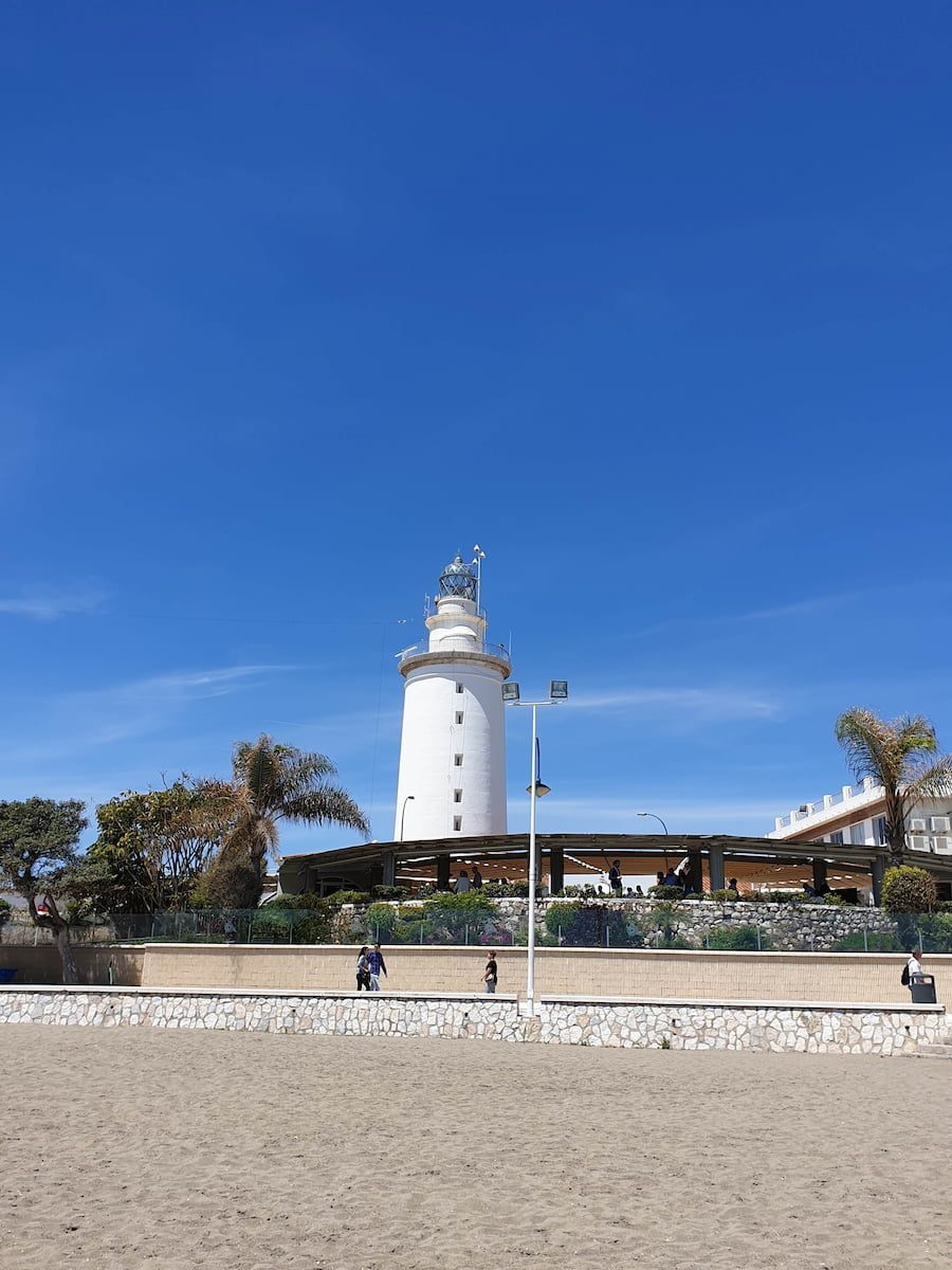 La Farola lighthouse behind the sand and promenade at La Malagueta.