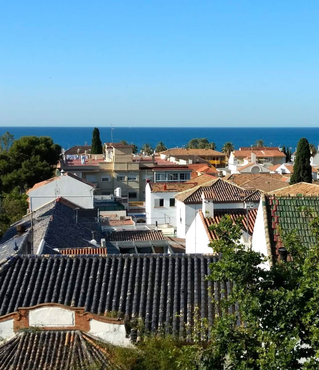 Low rooftops in Pedregalejo with the sea beyond.