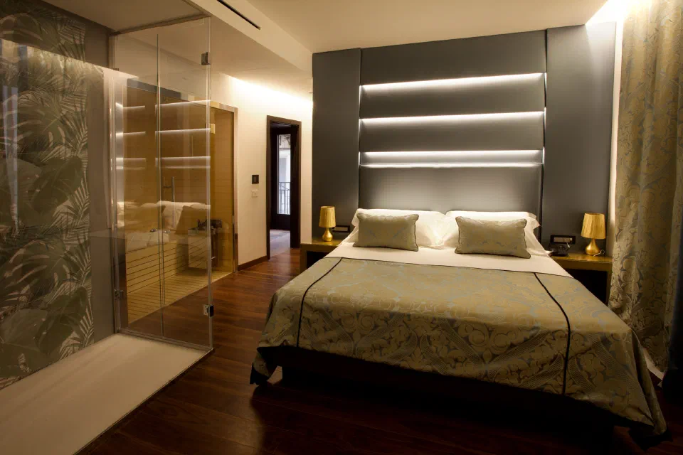 Double bed and illuminated headboard in a Suite with Sauna at Palazzo Cartari, Palermo.