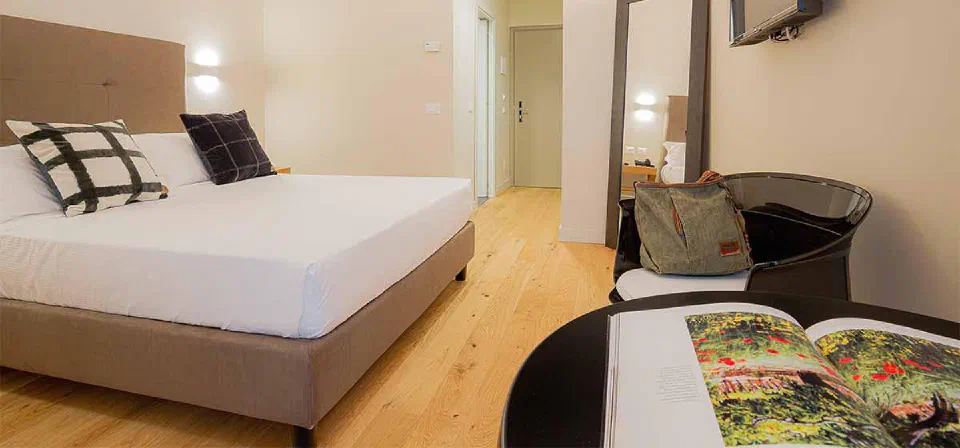 Double bed and light wooden floor in a Standard room at Hotel Politeama, Palermo.