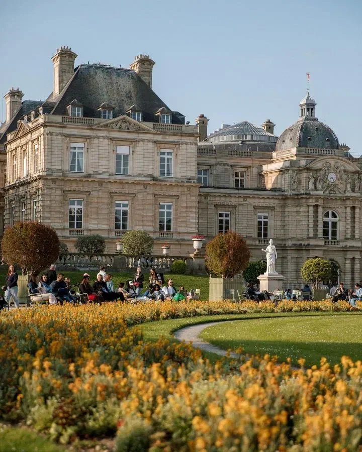 Flowerbeds and visitors in front of Luxembourg Palace in Jardin du Luxembourg.