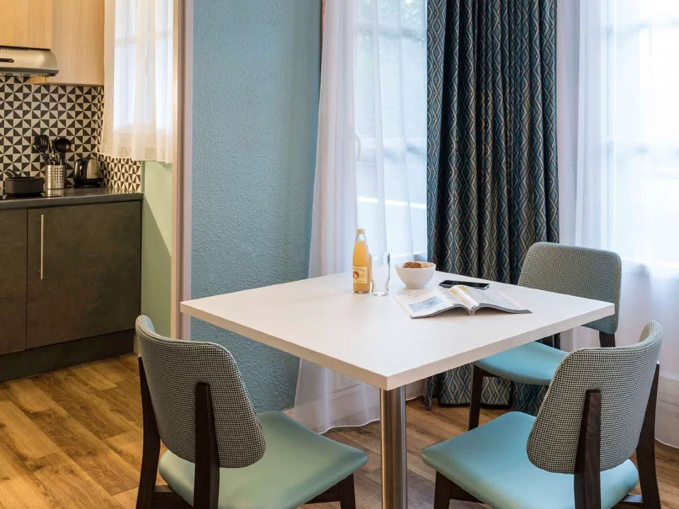Dining table beside an equipped kitchenette at Adagio Paris Montmartre.