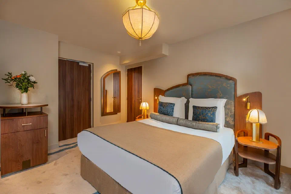Blue headboard and warm lighting in an Executive Eiffel Tower room at La Bourdonnais.