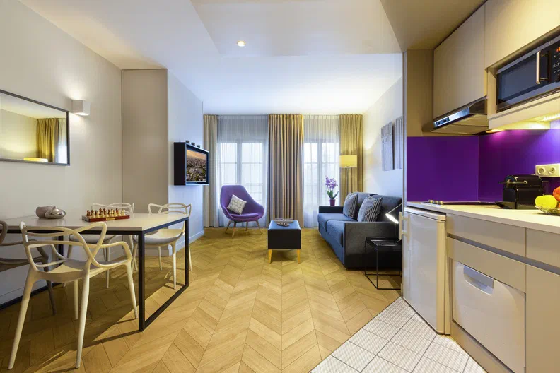 Living and dining area beside a fitted kitchen at Citadines Opéra Paris.
