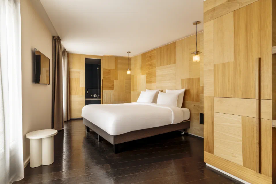 Wood-panelled La Junior room at Le Citizen with a double bed and tall window.