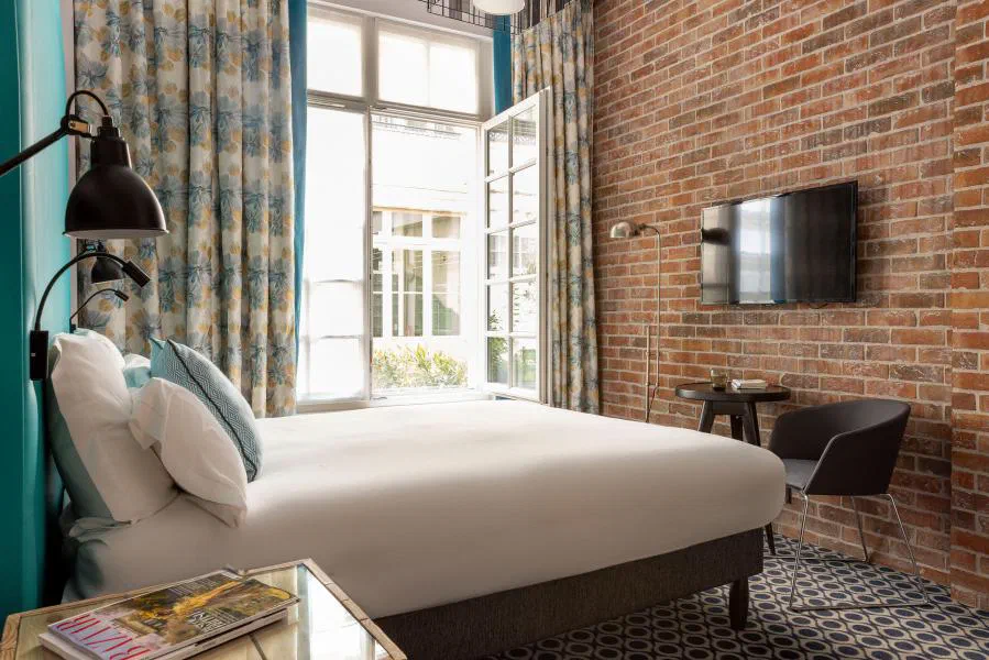 Club room at Hôtel Fabric with an exposed-brick wall and large courtyard window.