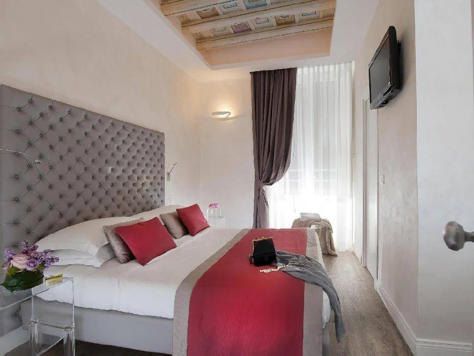A bedroom with a decorated wooden ceiling at Hotel Navona.