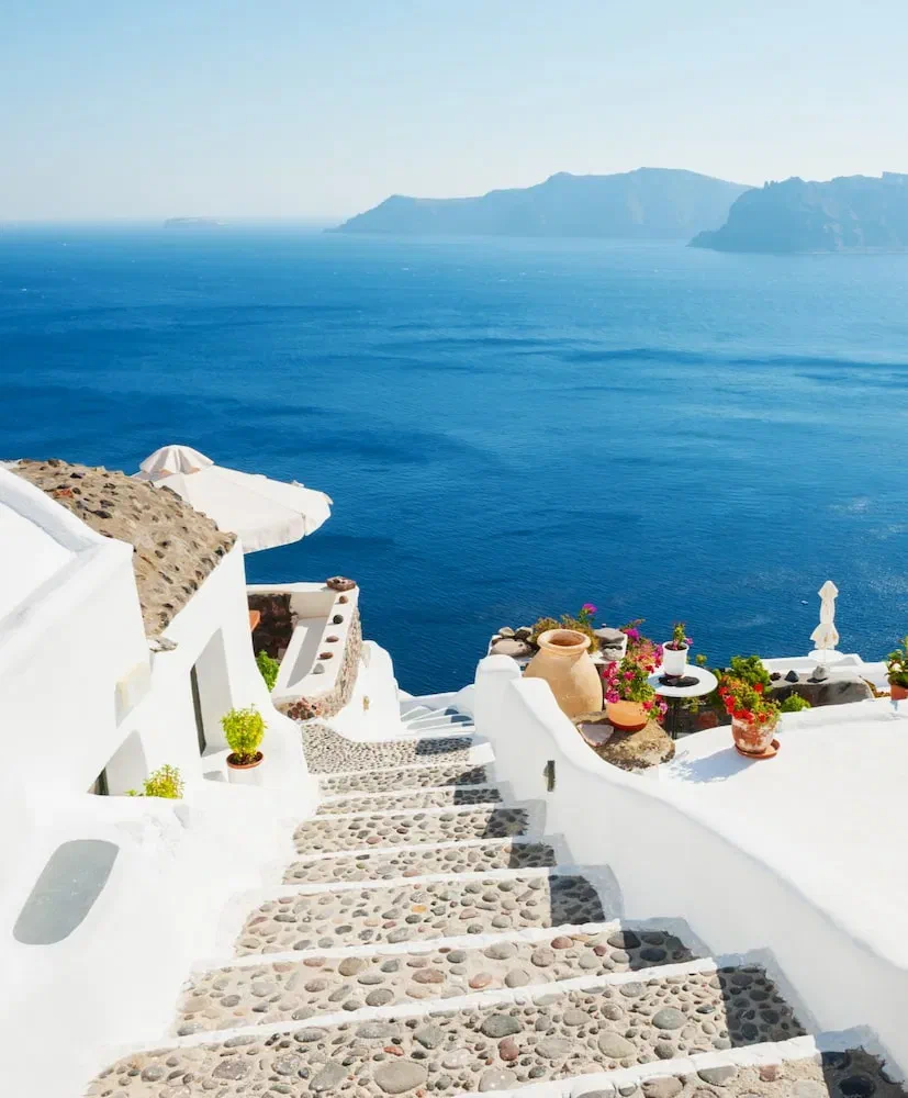Whitewashed steps and terraces descend towards the caldera in Oia, with the Aegean Sea beyond.