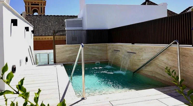 Compact rooftop pool with water jets and rooftops at Hotel Amadeus Sevilla.