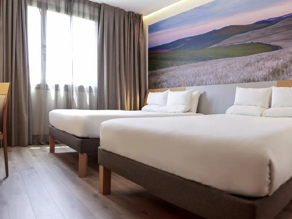 Two double beds beneath a landscape mural in a Superior room at Novotel Sevilla.