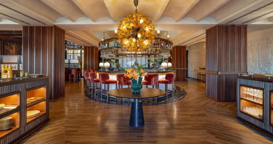 Circular bar, red velvet stools and a golden pendant light in the lobby of Only YOU Hotel Sevilla.