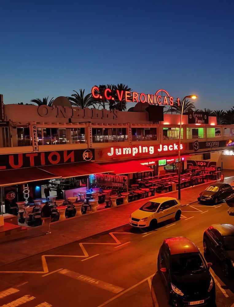 Neon signs around Las Verónicas in Playa de las Américas at dusk.
