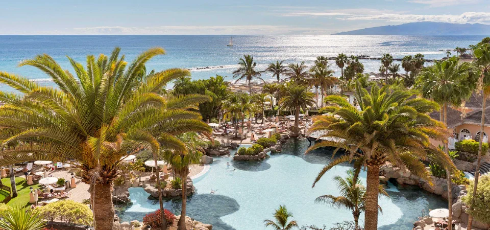 Pools and palm gardens at Bahía del Duque, with the beach and Atlantic beyond.