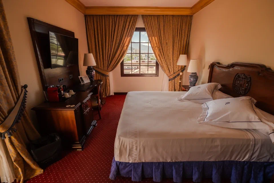 Warmly decorated Double Standard room at Europe Villa Cortés, with wooden furniture and rust-coloured curtains.