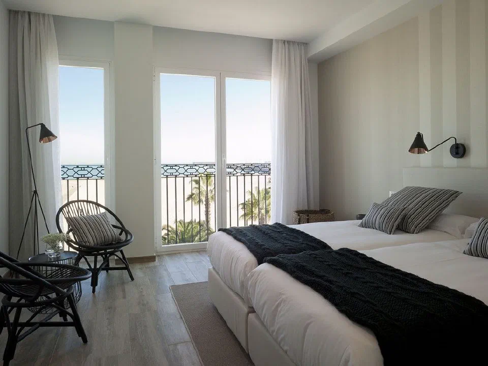 A Deluxe Vista Mar bedroom at Hotel Boutique Balandret, with the beach visible beyond the windows.