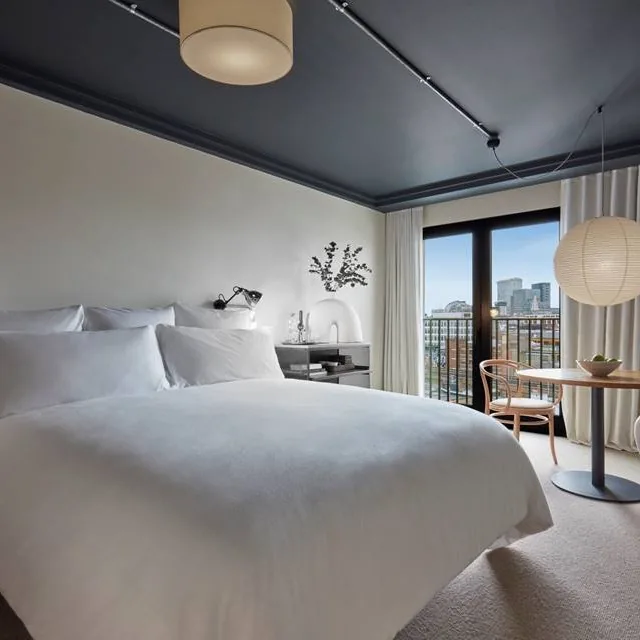 Studio Loft at One Hundred Shoreditch, showing its bed, seating area and large window with a Shoreditch view